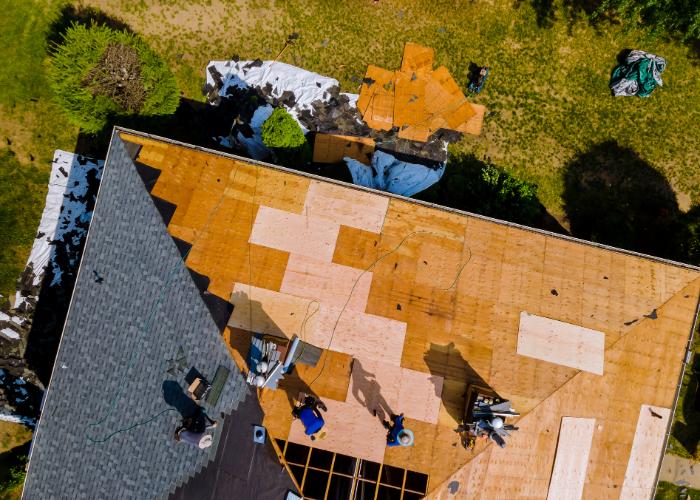 Workers performing tile roof repair in Cranston with partially replaced tiles visible from an aerial view.