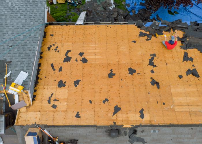 aerial view of a roof under repair, showing exposed wooden decking after the removal of old shingles in Cranston